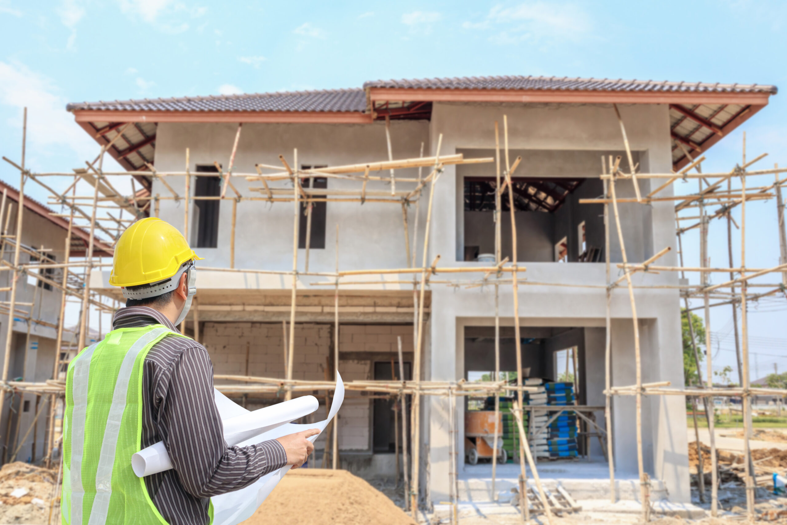 trabajador de arquitecto ingeniero profesional con casco protector y papel de planos en el fondo del sitio de construccion de edificios de viviendas scaled